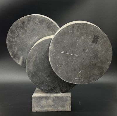 une sculpture composée de trois disques posés sur un socle, sur fond noir