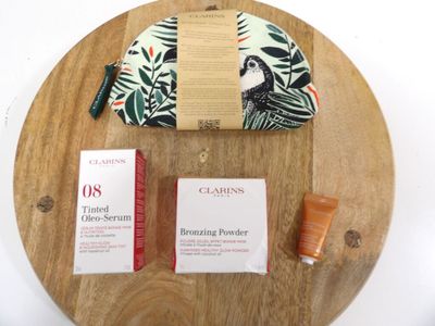 a wooden tray with a cosmetic bag and a bottle of lotion on it