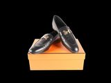 black leather loafers with gold buckles on top of an orange box