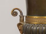 a large bronze vase on a stand with a bird on it