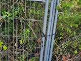 a fence that has a sign on it in front of some bushes