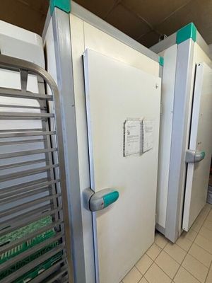 a row of white refrigerators in a kitchen with green handles