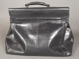 grey leather bag with zippers and handles on a grey surface