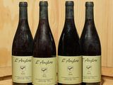 quatre bouteilles de vin sont alignées sur un tonneau en bois
