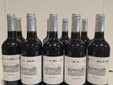 six bottles of red wine are lined up on a counter