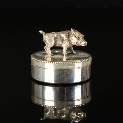 une figurine en argent représentant un chien posée sur une pièce de monnaie