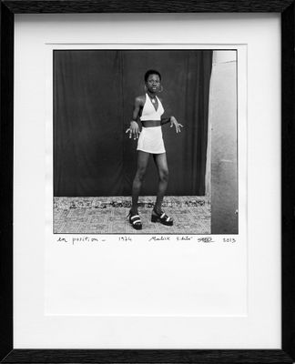 black and white photograph of a woman in a tennis outfit holding a tennis racquet