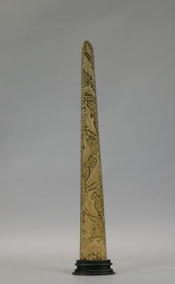 carved obelisk on a black stand with a white background