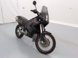 une moto noire garée dans une pièce aux murs blancs