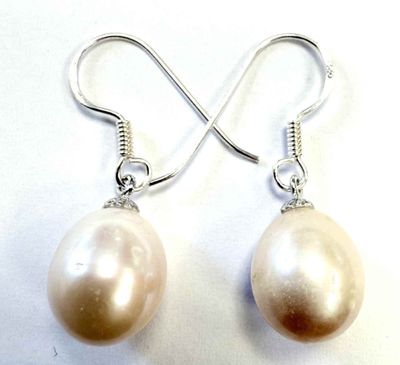 boucles d'oreilles argentées et perles blanches sur fond blanc