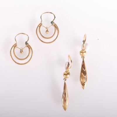 trois paires de boucles d'oreilles en or et une boucle d'oreille en perle posées sur un fond blanc