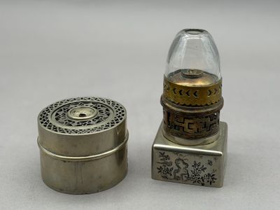 un petit récipient en argent muni d'un couvercle en verre, à côté d'un autre petit récipient en argent muni d'un couvercle en verre