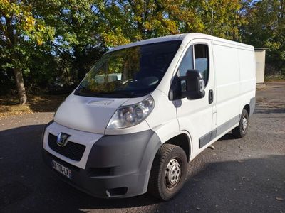 une camionnette blanche garée sur un parking avec des arbres en arrière-plan