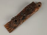 une vieille sculpture en bois représentant un oiseau sur lequel est posée une fleur