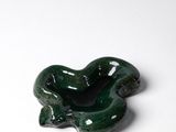 un petit objet vert posé sur une surface blanche