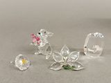 trois figurines en cristal représentant des souris et des fleurs, posées sur un fond gris
