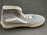 grey and white high top sneakers with white laces on a black surface