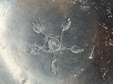 a silver plate with a design on it sitting on a table