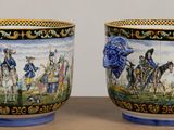 two vases sitting on a table with a painting on them