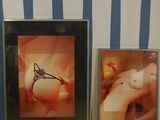 two framed pictures of a naked woman and a clock on a wall