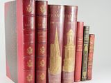 several old books are lined up on a shelf in a row