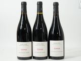 trois bouteilles de vin rouge sont alignées sur une surface blanche