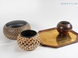 trois vases posés sur un plateau, sur une surface blanche
