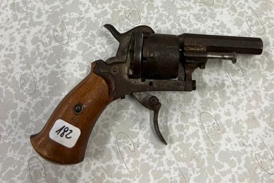 un vieux revolver muni d'une étiquette, posé sur une table