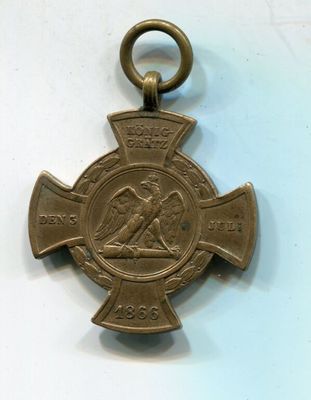an old bronze medal with a cross on it on a white surface