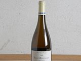 une bouteille de vin posée sur une table, avec un mur blanc en arrière-plan