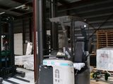un chariot élévateur dans un entrepôt rempli de palettes et de cartons