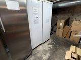 deux réfrigérateurs qui se trouvent dans une pièce où il y a des cartons par terre