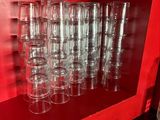 bottles and glasses are lined up on a red shelf in a room