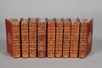 six old books are lined up in a row on a table