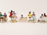 several figurines of people sitting on a bench with a white background