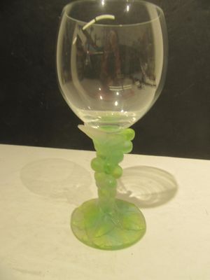 a green wine glass sitting on a table next to a black wall