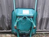 a green wheelbarrow with a sign on the side of it