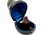 une bague dans un écrin noir, sertie d'une pierre rouge