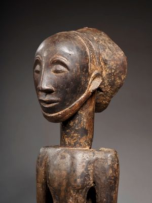 une sculpture en bois représentant une femme coiffée d'une coiffe