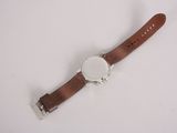 watch on a white surface with a brown leather strap