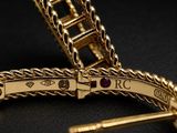 an image of a close up of a gold bracelet with a red stone