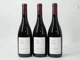 trois bouteilles de vin rouge posées l'une à côté de l'autre sur une surface blanche