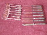 several forks and knives are lined up on a pink cloth