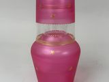 vase en verre rose orné d'étoiles dorées sur un fond blanc