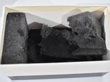 a white box filled with black charcoal sitting on a table
