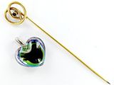une broche en forme de cœur et un bâton posés sur une surface blanche