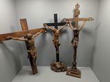 trois crucifix en bois posés sur une étagère dans une pièce