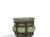 a small vase with green stones in it on a white surface