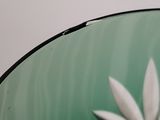 a close up of a green vase with a white flower on it
