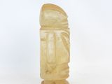 yellow jade carving of a man on a pedestal on a white background